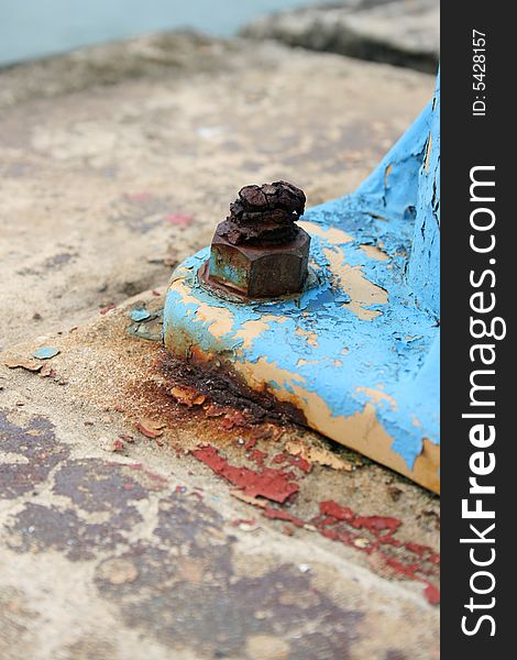 Rusted old bolt and on a blue lamp post foot