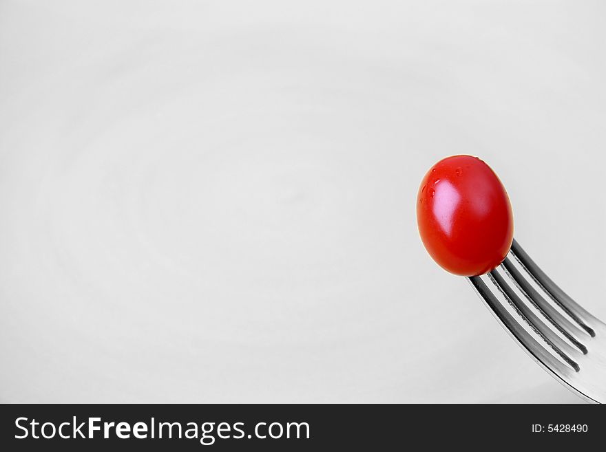 Single tomato on a fork against a yellow plate