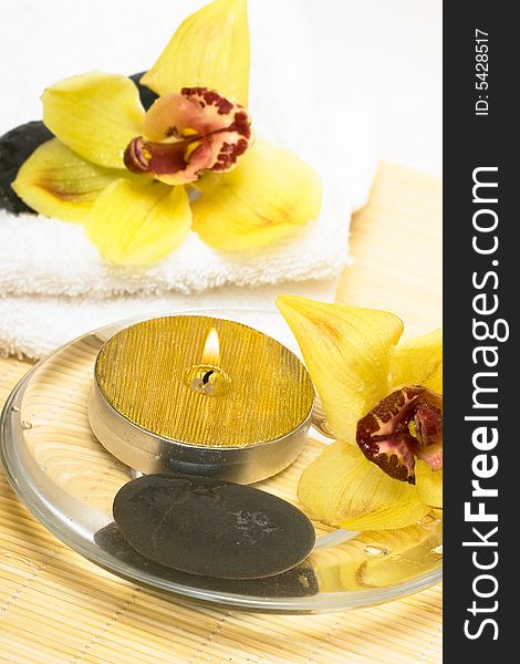 Candle in water with yellow orchids and towel. Candle in water with yellow orchids and towel
