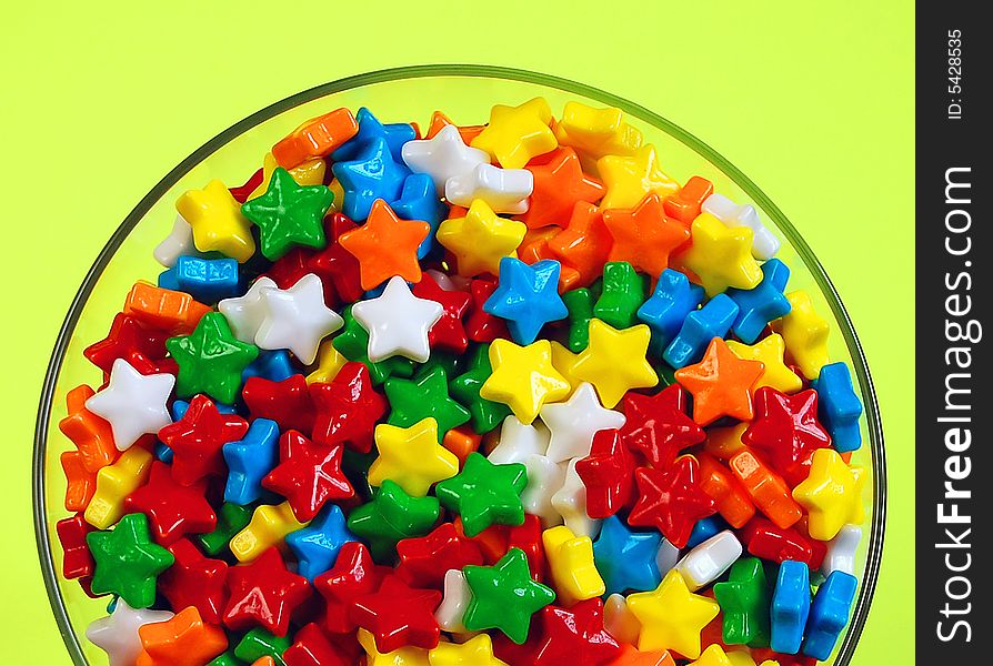 Glass dish of candy stars against yellow background. Glass dish of candy stars against yellow background