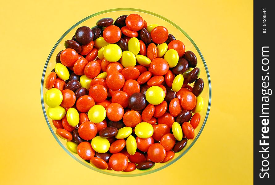 Glass dish of candies against brown background. Glass dish of candies against brown background