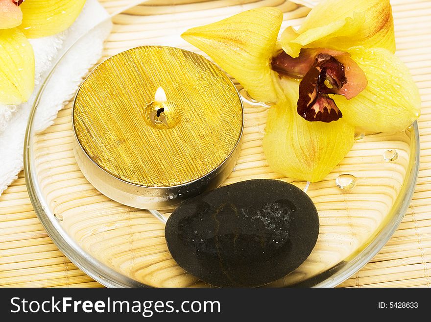 Candle in water with yellow orchids and towel. Candle in water with yellow orchids and towel