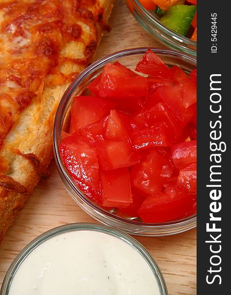 Bowl of diced tomatoes with veggies and cheesebread pizza.