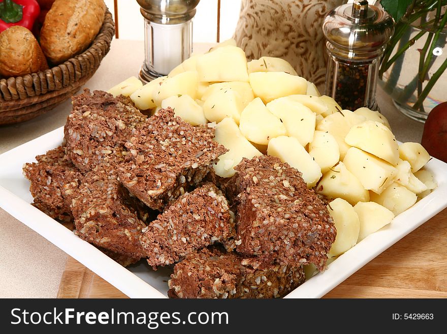 Platter with meatloaf and boiled herb potatoes in kitchen or restaurant. Platter with meatloaf and boiled herb potatoes in kitchen or restaurant.