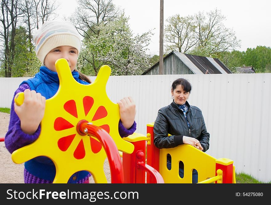 Smiling Mother Watching Play On The Playground Daughter