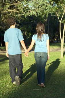 Young Couple Walking Through A Park - Vertical Stock Photo