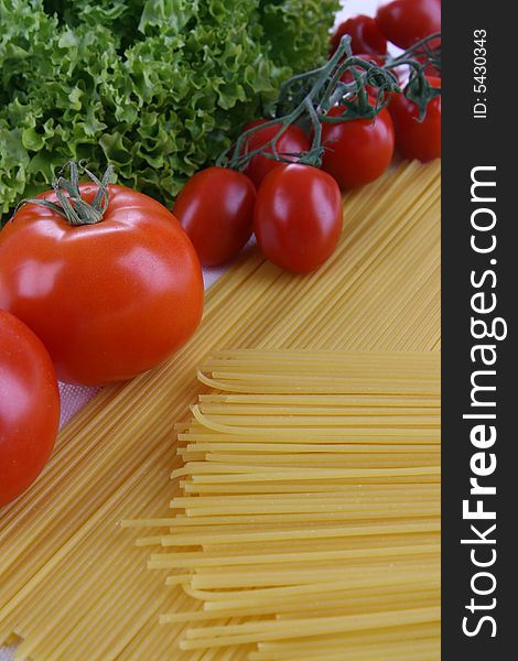Pasta, red tomatoes and lettuce on the table. Pasta, red tomatoes and lettuce on the table