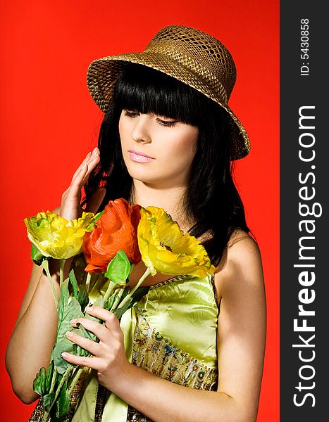 Girl in hat with flowers on red background