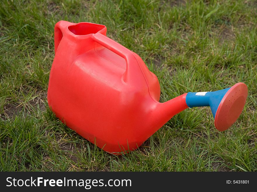 Red watering-pot on green grass