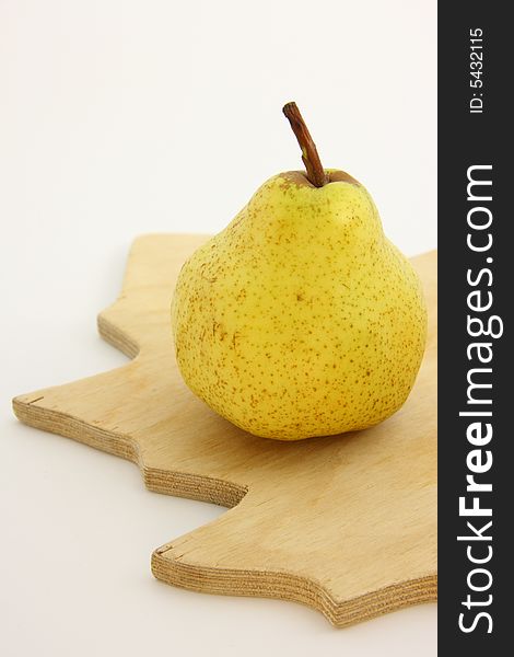 Yellow pear on woody kitchen board.