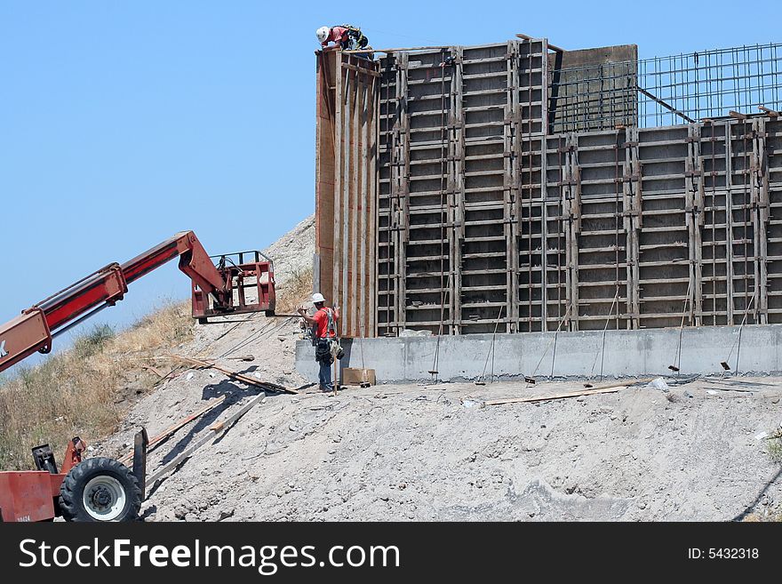 Two construction workers on the job working on a freeway overpass. Two construction workers on the job working on a freeway overpass