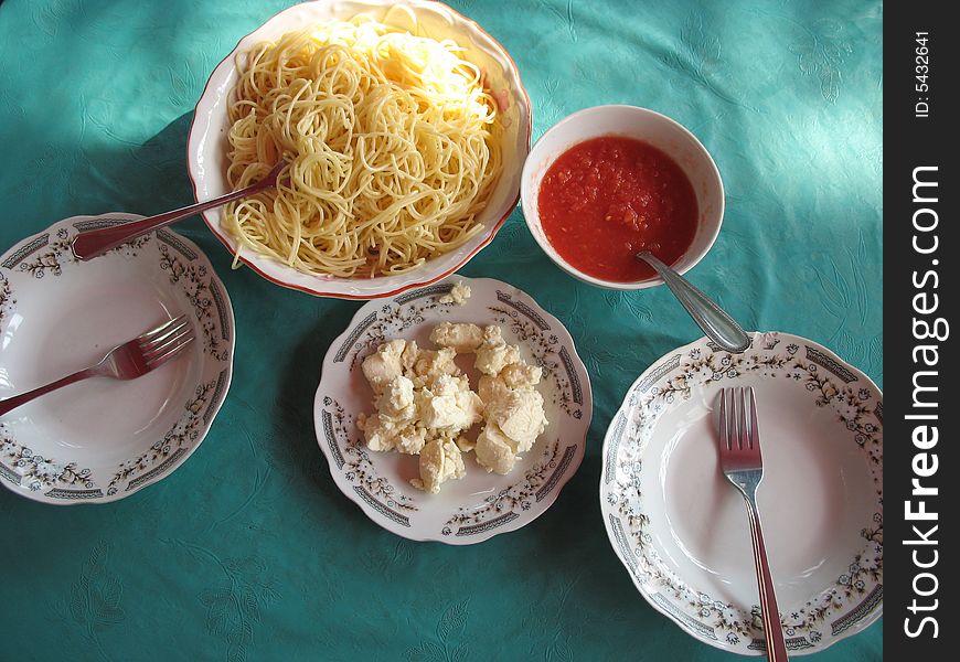 There is a bowl of spaghetti and two plates on the table
