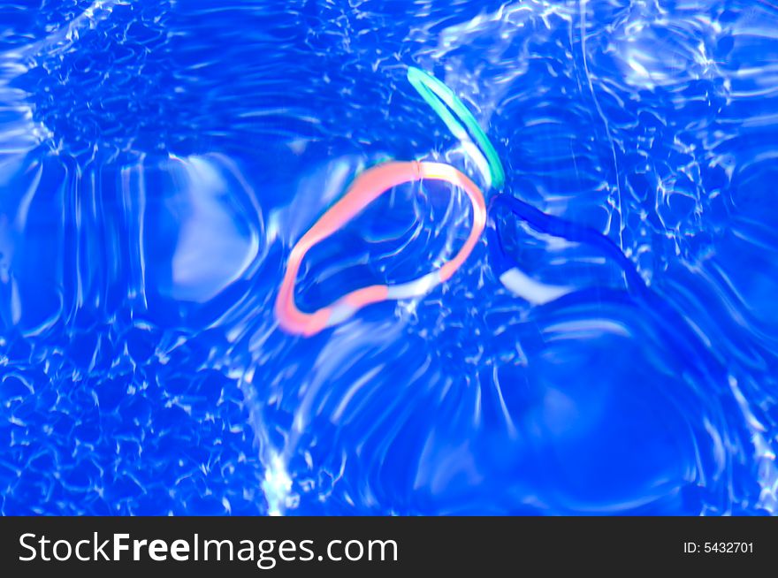 Three different colored rings sit at the bottom of a swimming pool during heavy wave action. Three different colored rings sit at the bottom of a swimming pool during heavy wave action.