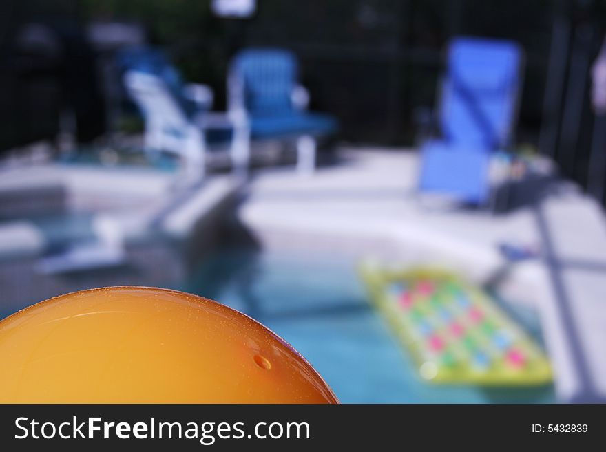 Abstract photo of a private pool, focus is on pool ball and deck chairs and pool is out of focus in bakcground. Abstract photo of a private pool, focus is on pool ball and deck chairs and pool is out of focus in bakcground