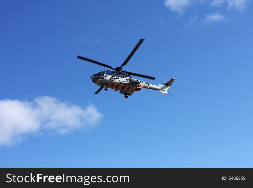 Big helicopter flying overhead, blue sky with stray clouds