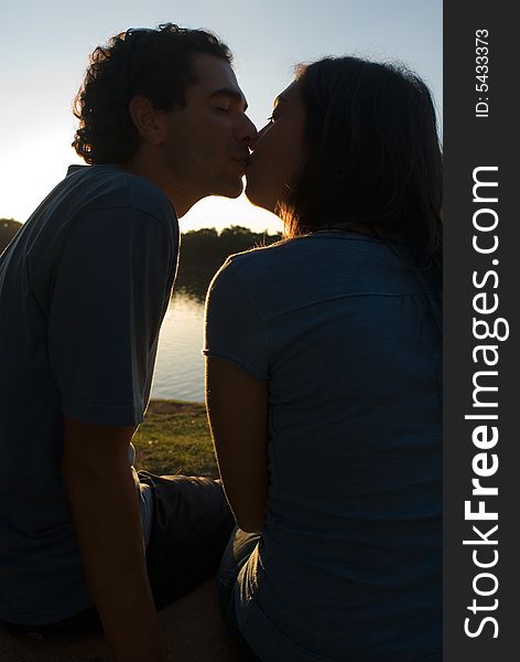 Dark Silhouette of a couple kissing at sunset. Vertically framed photograph. Dark Silhouette of a couple kissing at sunset. Vertically framed photograph.