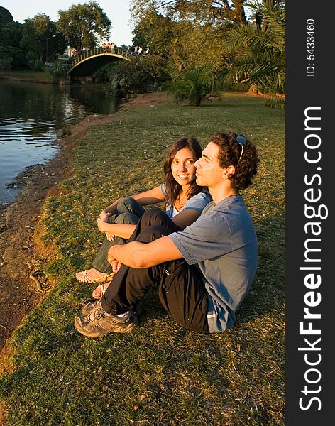 Couple sits by a river. Vertically framed shot. Couple sits by a river. Vertically framed shot.