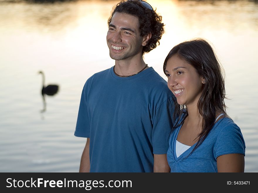 Happy, smiling couple standing in front of a pond and a swan. Horizontal. Happy, smiling couple standing in front of a pond and a swan. Horizontal