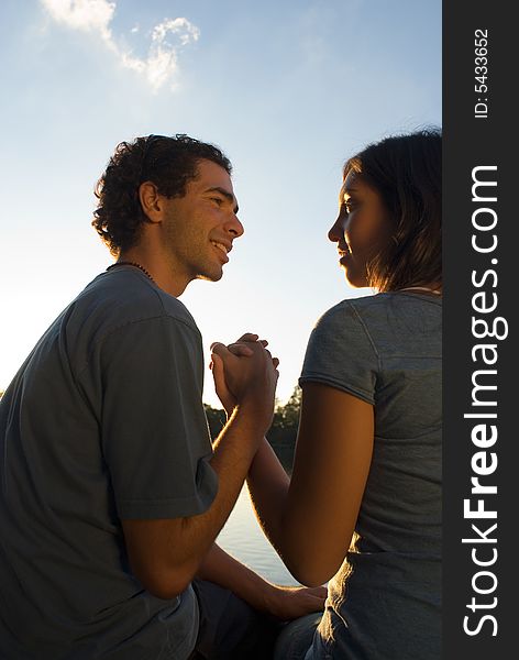 Couple Holding Hands under a Blue Sky while they look at each other happily. Vertically framed photograph. Couple Holding Hands under a Blue Sky while they look at each other happily. Vertically framed photograph.