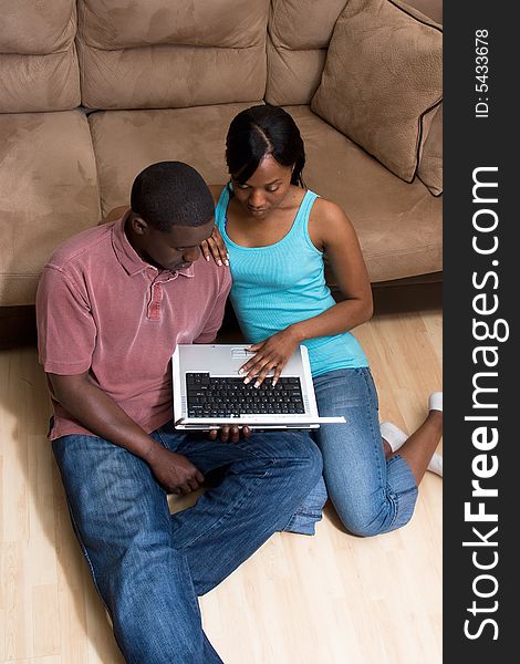 Couple Sitting in front of Couch with Laptop Com
