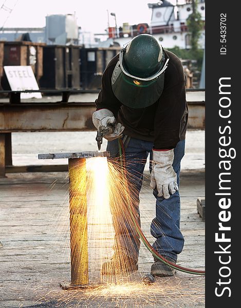 A welder working a torch at shipyard. A welder working a torch at shipyard