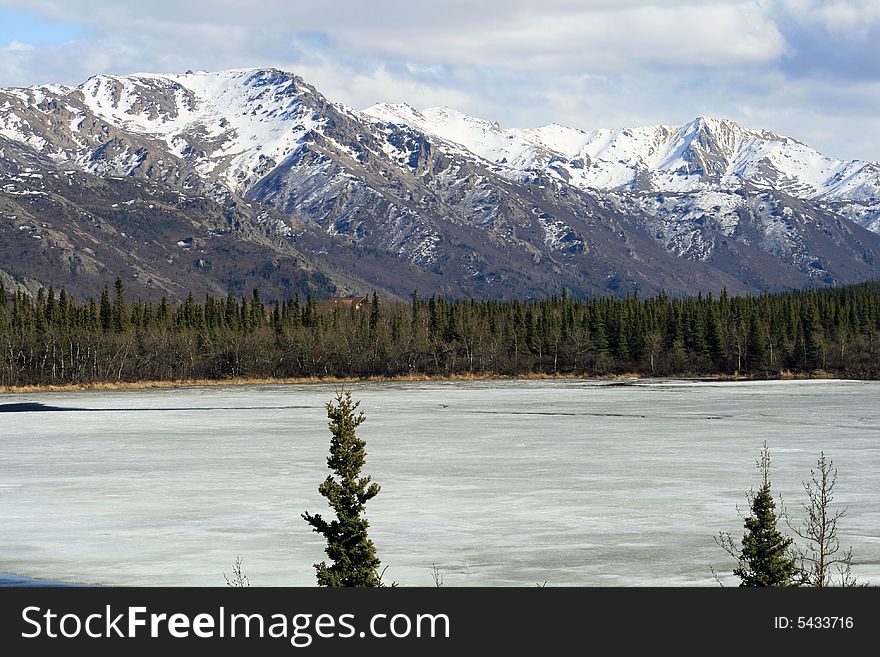 Snow covered mountains and a frozen pond in May. Snow covered mountains and a frozen pond in May.