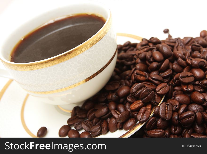 A side view shot of a  cup of coffee isolated on white with coffeebeans flowing  from it. A side view shot of a  cup of coffee isolated on white with coffeebeans flowing  from it