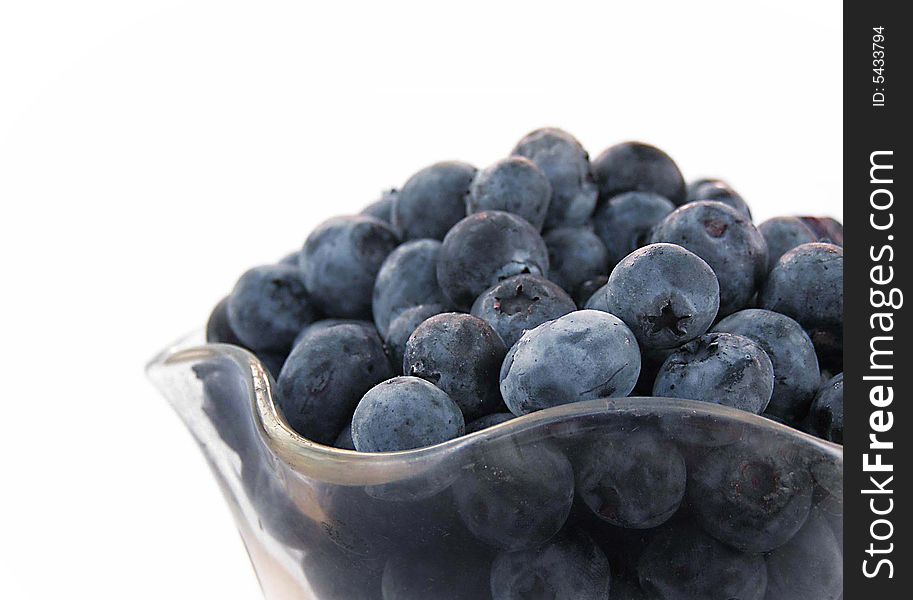 Glass bowl of blueberries taken on white background.