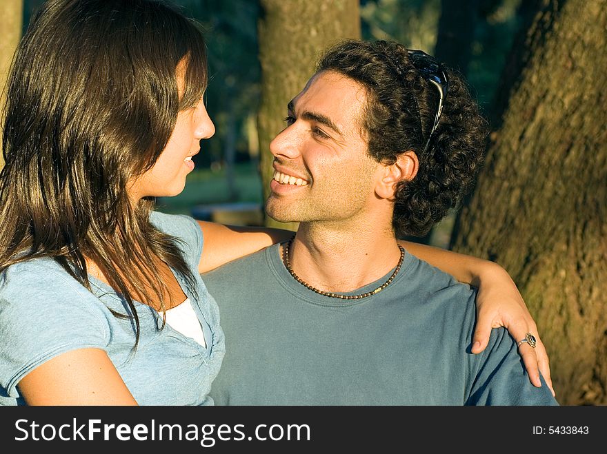 Happy, couple in the woods. She she has her arm around him as they look at each other and smile. Horizontally framed photograph. Happy, couple in the woods. She she has her arm around him as they look at each other and smile. Horizontally framed photograph