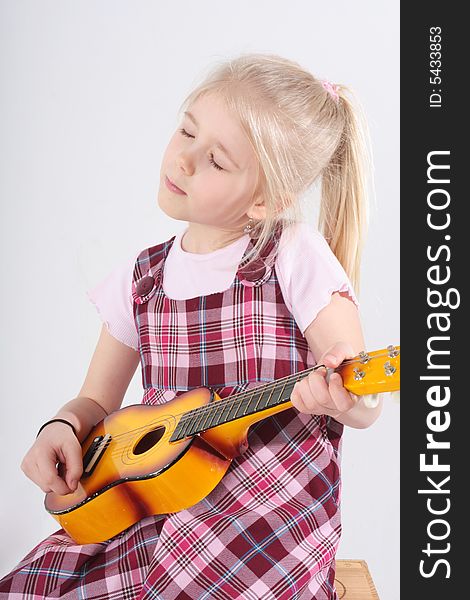 Small girl playing a toy guitar. Small girl playing a toy guitar