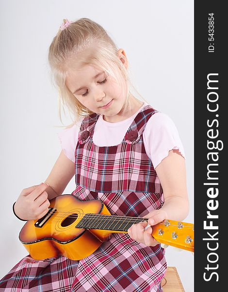 Small girl playing a toy guitar. Small girl playing a toy guitar