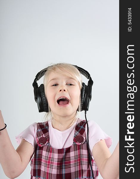 Small girl listening to music on headset and singing along. Small girl listening to music on headset and singing along