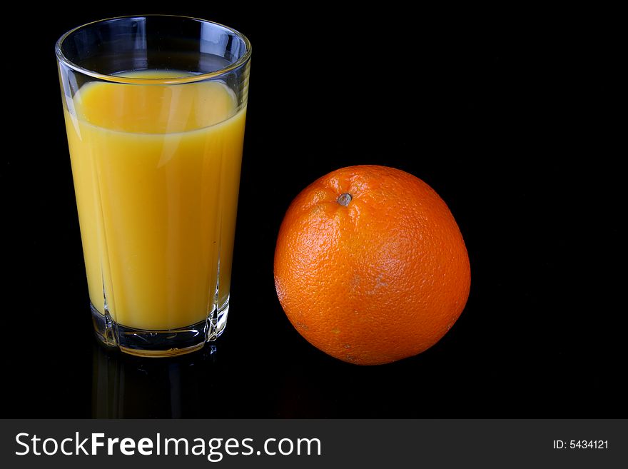 Fresh orange juice in glass with orange fruit next to it isolated on black, shot in studio. Fresh orange juice in glass with orange fruit next to it isolated on black, shot in studio