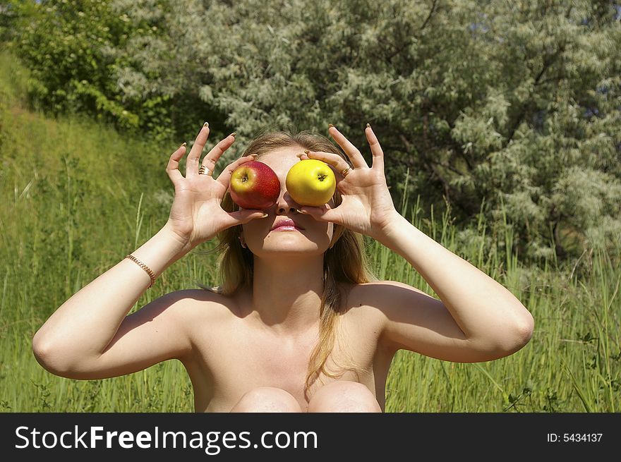 A young cute woman holding up some fruit. A young cute woman holding up some fruit