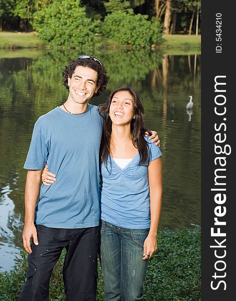 Happy, laughing couple standing in front of a pond. Vertical. Happy, laughing couple standing in front of a pond. Vertical