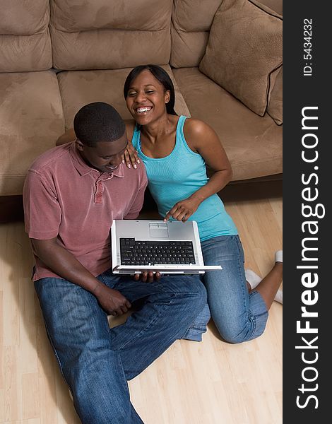 Couple Sitting in front of Couch with Laptop Com