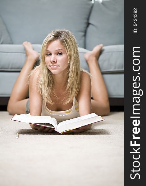 A beautiful young teenage girl reading on the floor. A beautiful young teenage girl reading on the floor