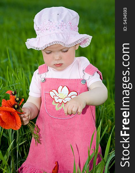Child with red flower amongst green grass