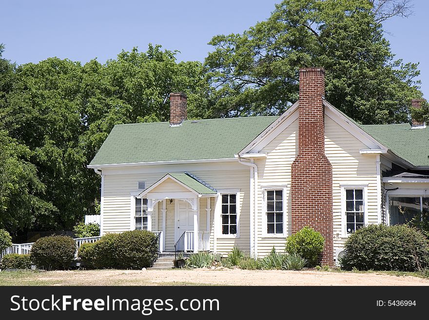 An old farmhouse with a green roof and a brick chimney. An old farmhouse with a green roof and a brick chimney