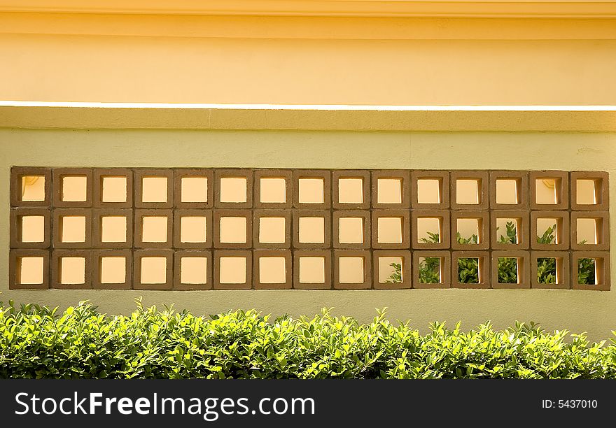 A yellow stucco wall and red tile blocks. A yellow stucco wall and red tile blocks