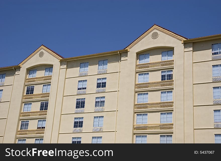 A nice yellow stucco hotel with red roofs against a blue sky. A nice yellow stucco hotel with red roofs against a blue sky