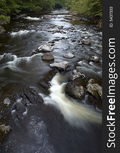 Water stream with the water flowing between rocks.