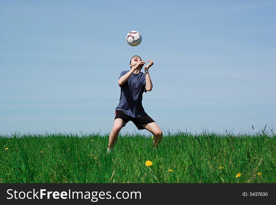 Happy boy playing football on sky background