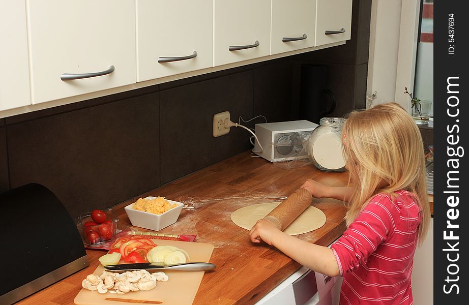 A little girl making pizza at home