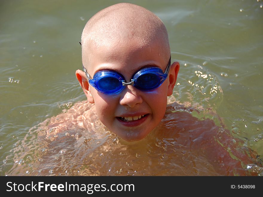 Happy young boy in googles is swimming in the lake