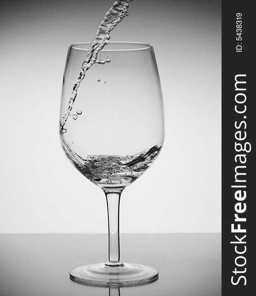 Water being poured into a glass with reflection on white background. Water being poured into a glass with reflection on white background.