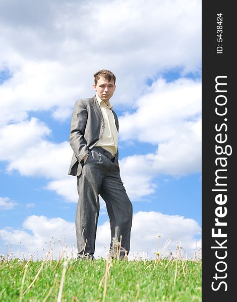 The young businessman standing on a green grass