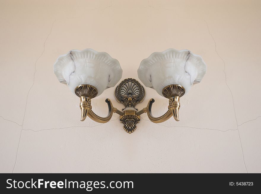 Old stylish bronze fixture on a cracked wall in a railway station. Old stylish bronze fixture on a cracked wall in a railway station.