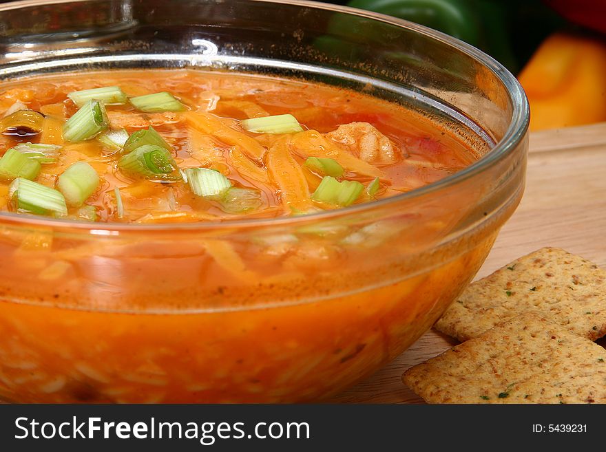 Bowl of Chicken Tortilla Soup garnished with shredded cheddar and green onions.