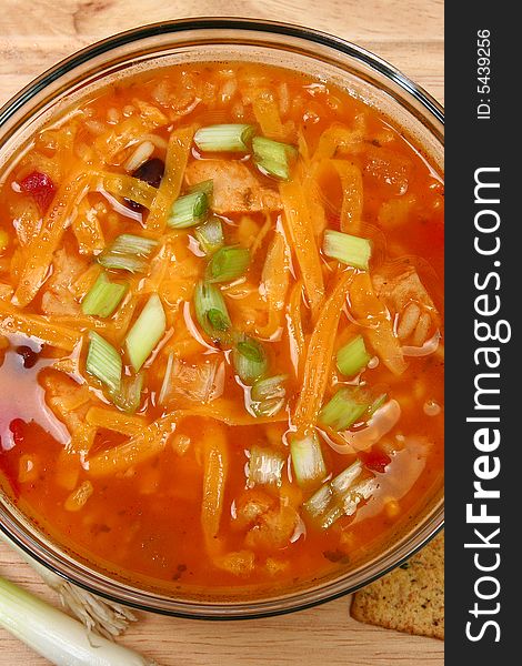 Bowl of Chicken Tortilla Soup garnished with shredded cheddar and green onions.